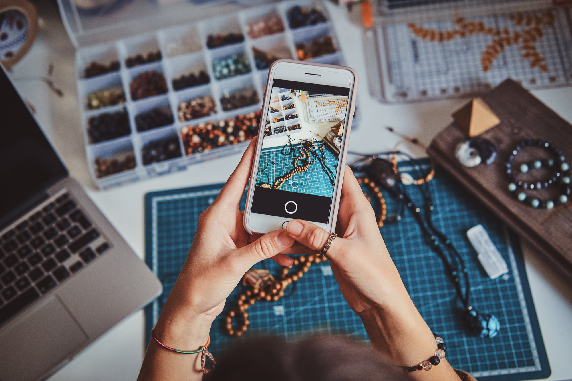 Creative jewellery artist is taking photo of her bracelet via mobile phone.