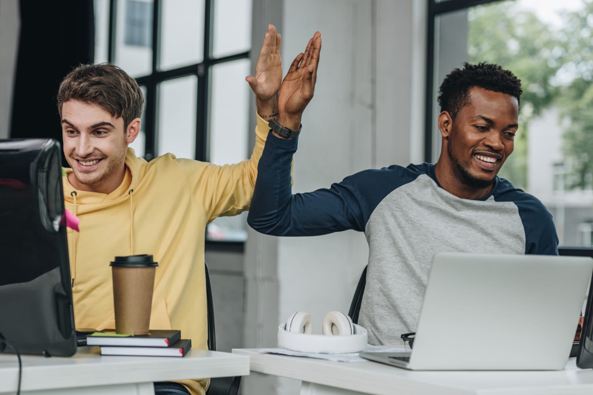 two men on laptops high fiving